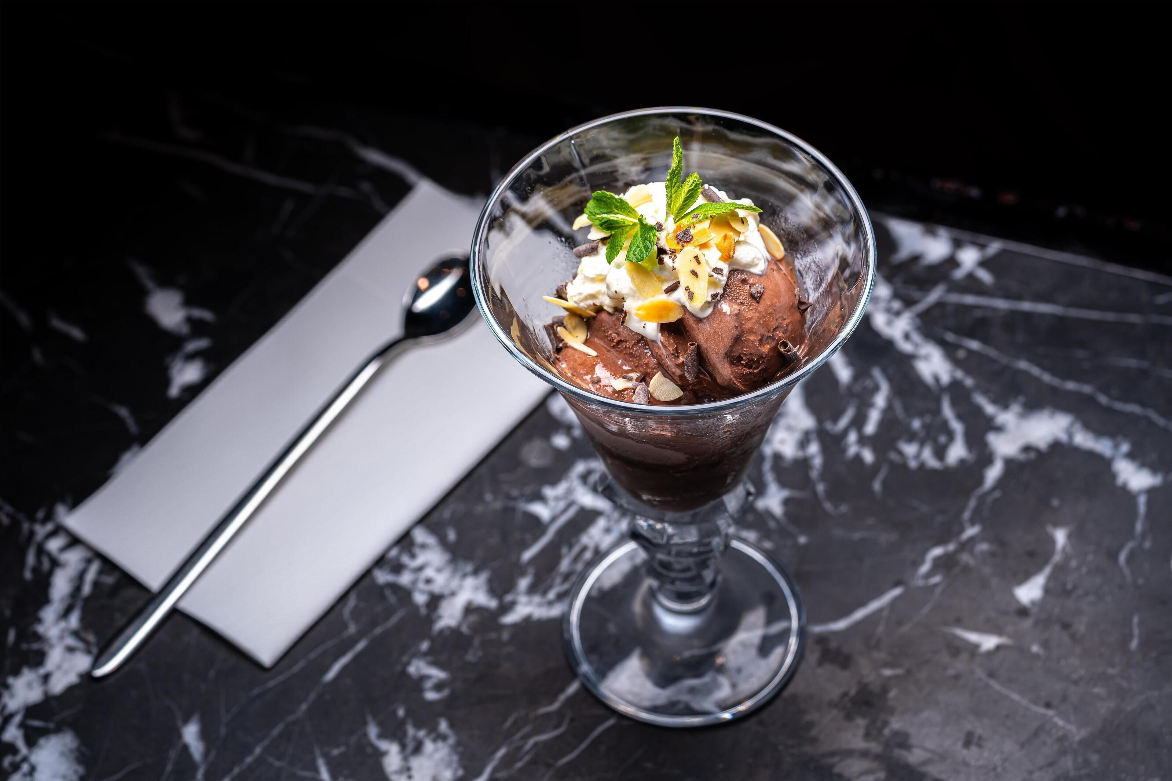 A dessert in a clear glass bowl on a marble surface.