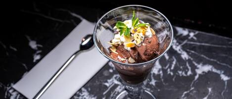 A dessert in a clear glass bowl on a marble surface.
