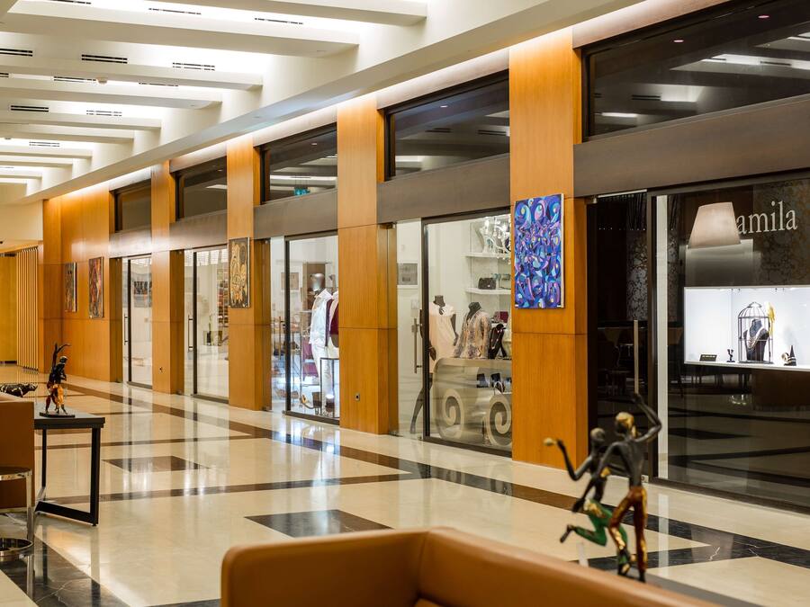 Un corredor moderno en un centro comercial con paneles de madera, escaparates de vidrio y suelo pulido.