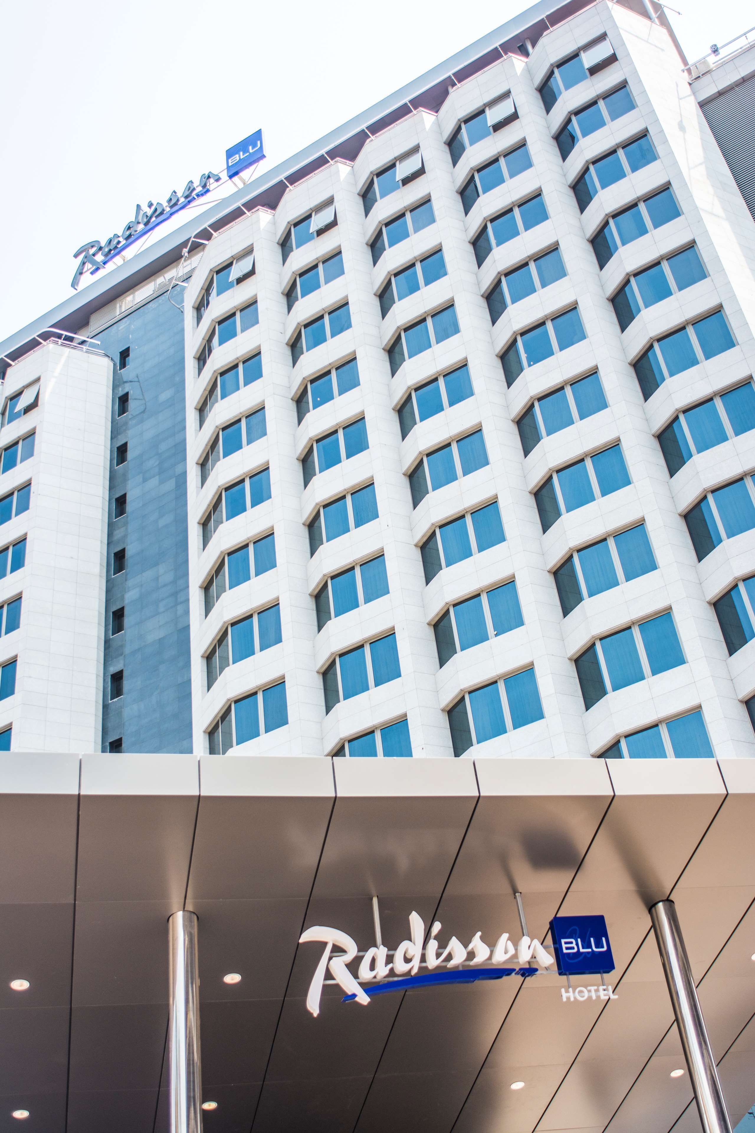 A Radisson Blu hotel building with a modern facade, large windows, and a prominent hotel sign.