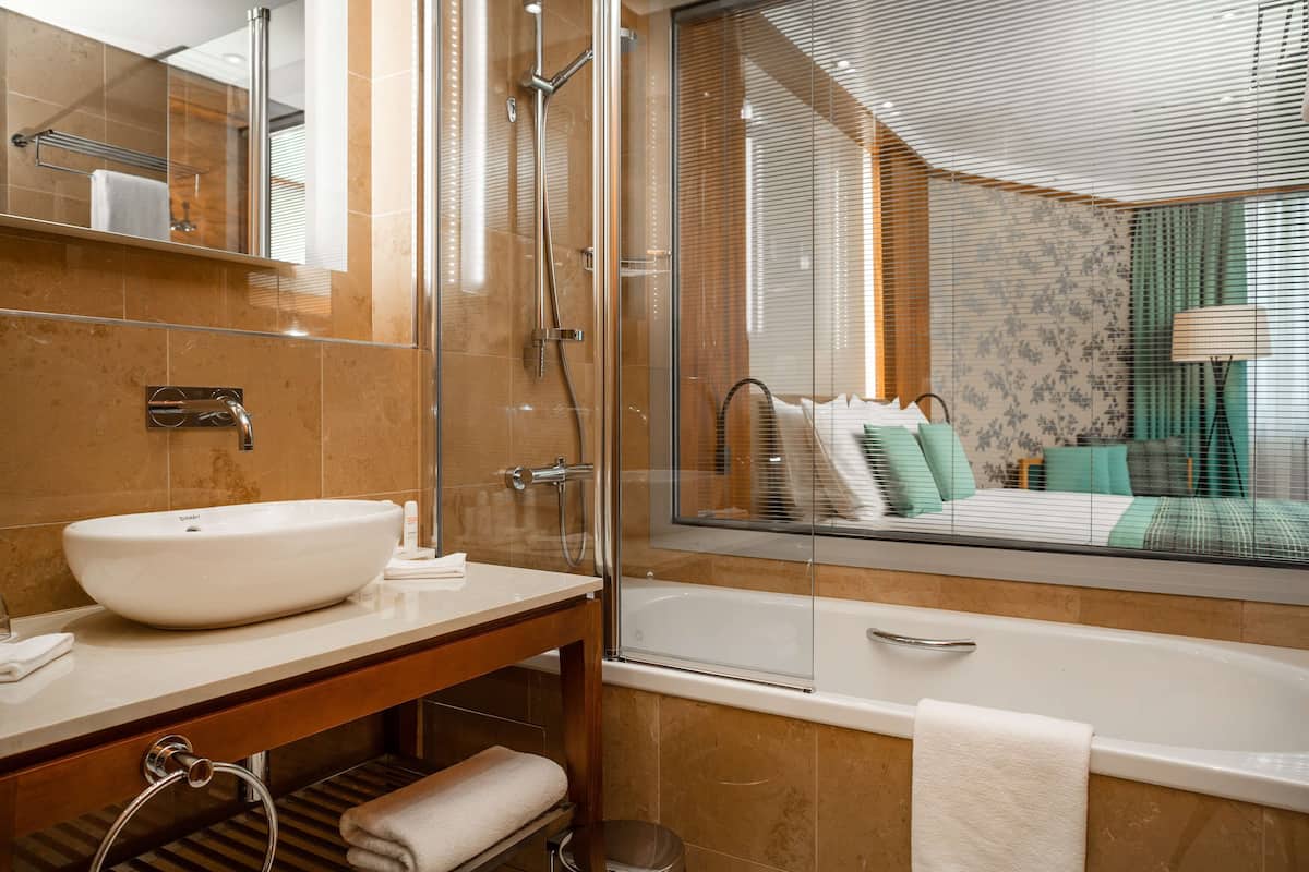 Une salle de bain moderne dotée d’une grande baignoire, d’une douche à parois de verre et d’un meuble-lavabo avec un grand évier.
