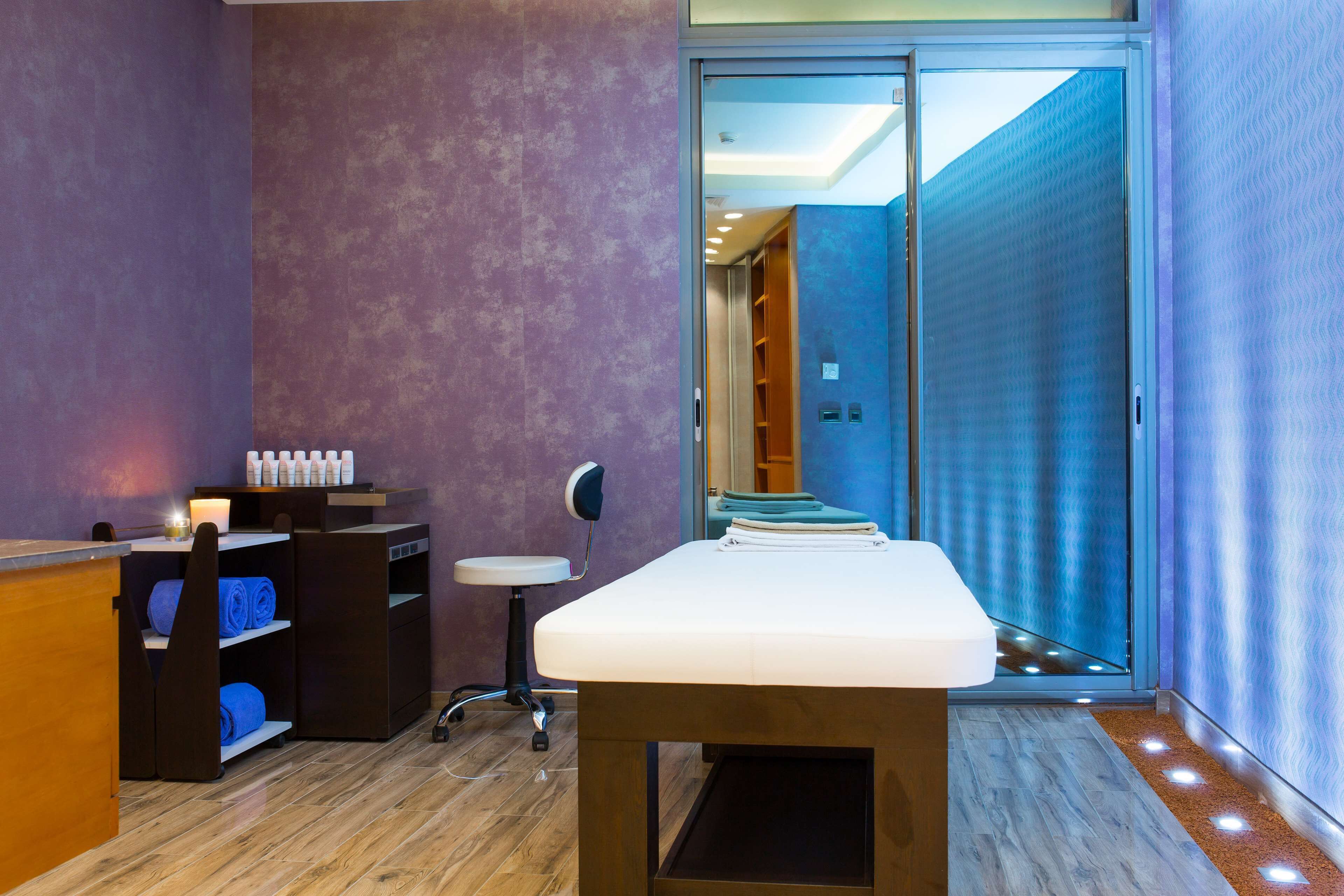 A room with a reception desk, a massage table, and a sliding glass door leading to a bathroom.