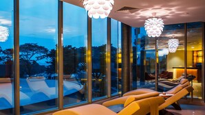 A modern lounge area with large windows, a pool, and contemporary lighting fixtures. - Radisson Blu M'Bamou Palace Hotel (Brazzaville)