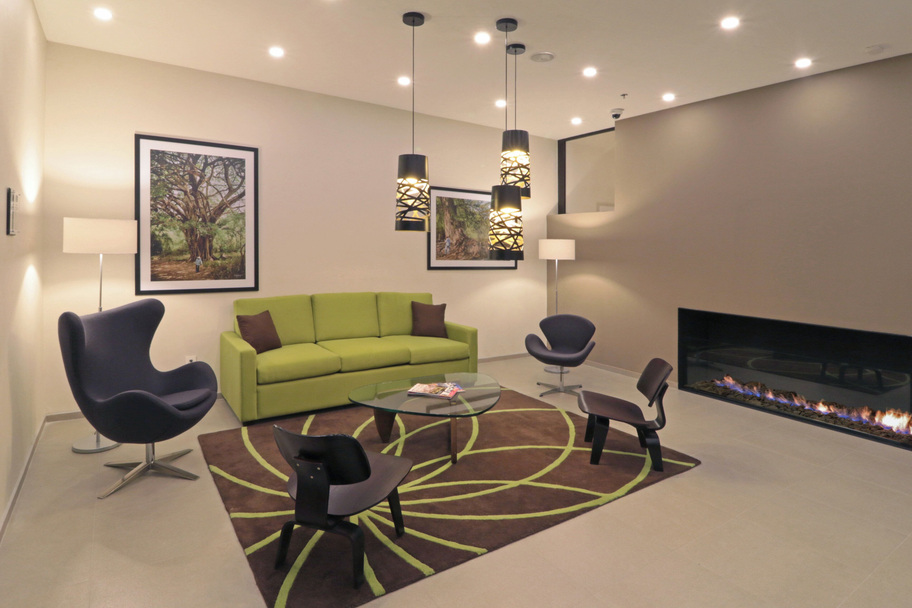 A modern living room with a green sofa, two armchairs, a coffee table, and a fireplace.