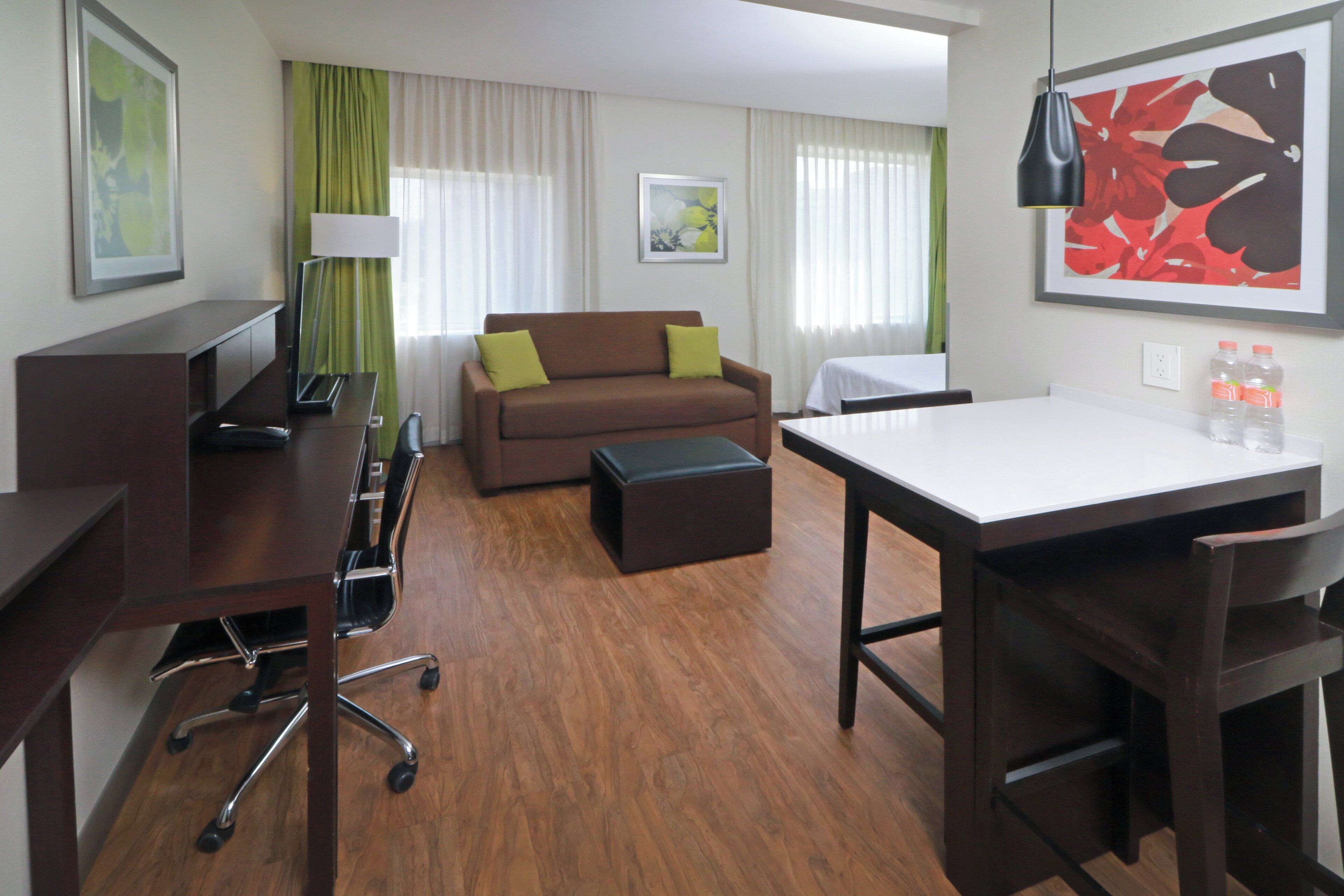 A hotel room with a desk, a sofa, a coffee table, and a bed.