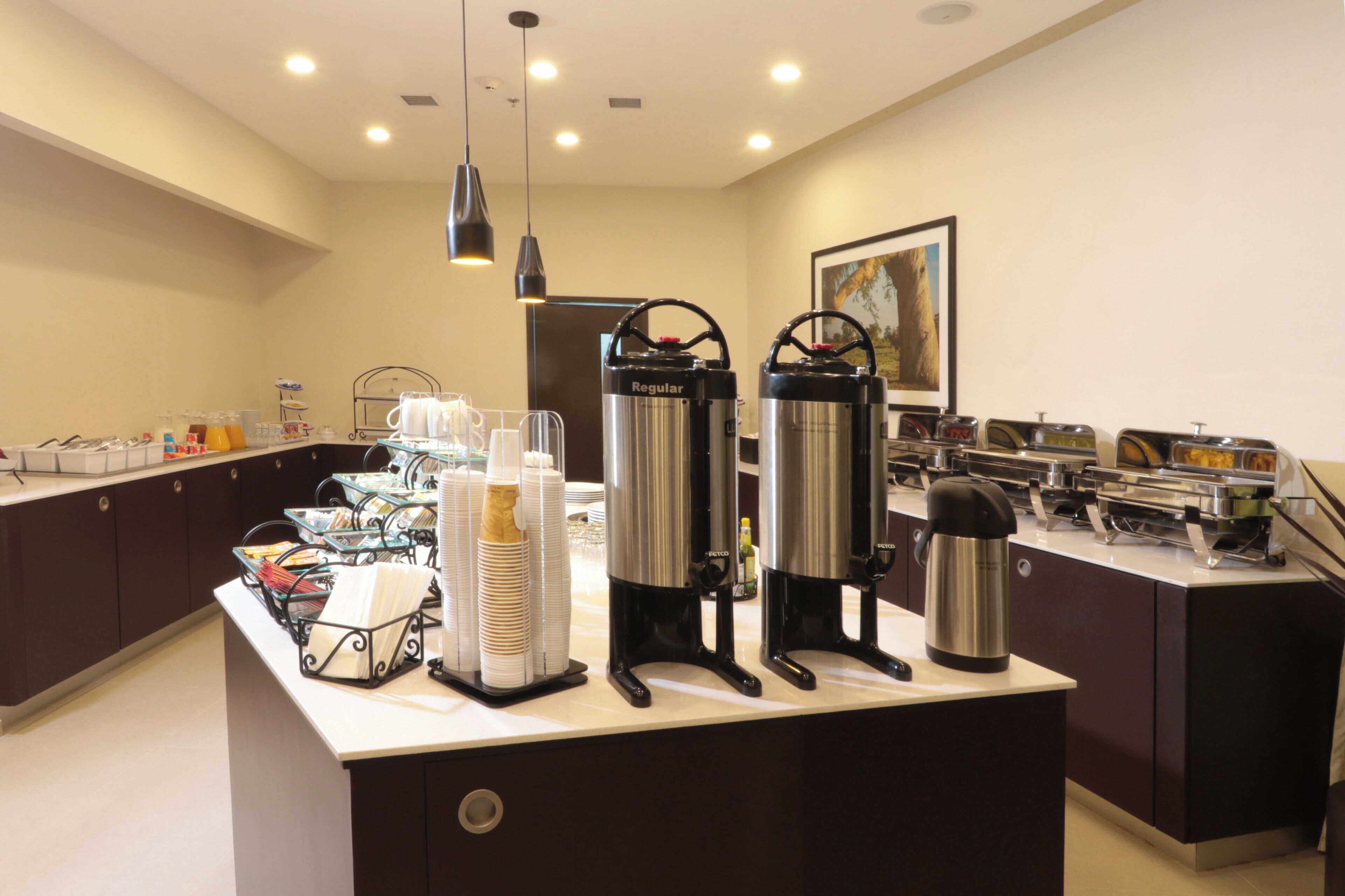 A buffet setup with various food containers and a coffee station.