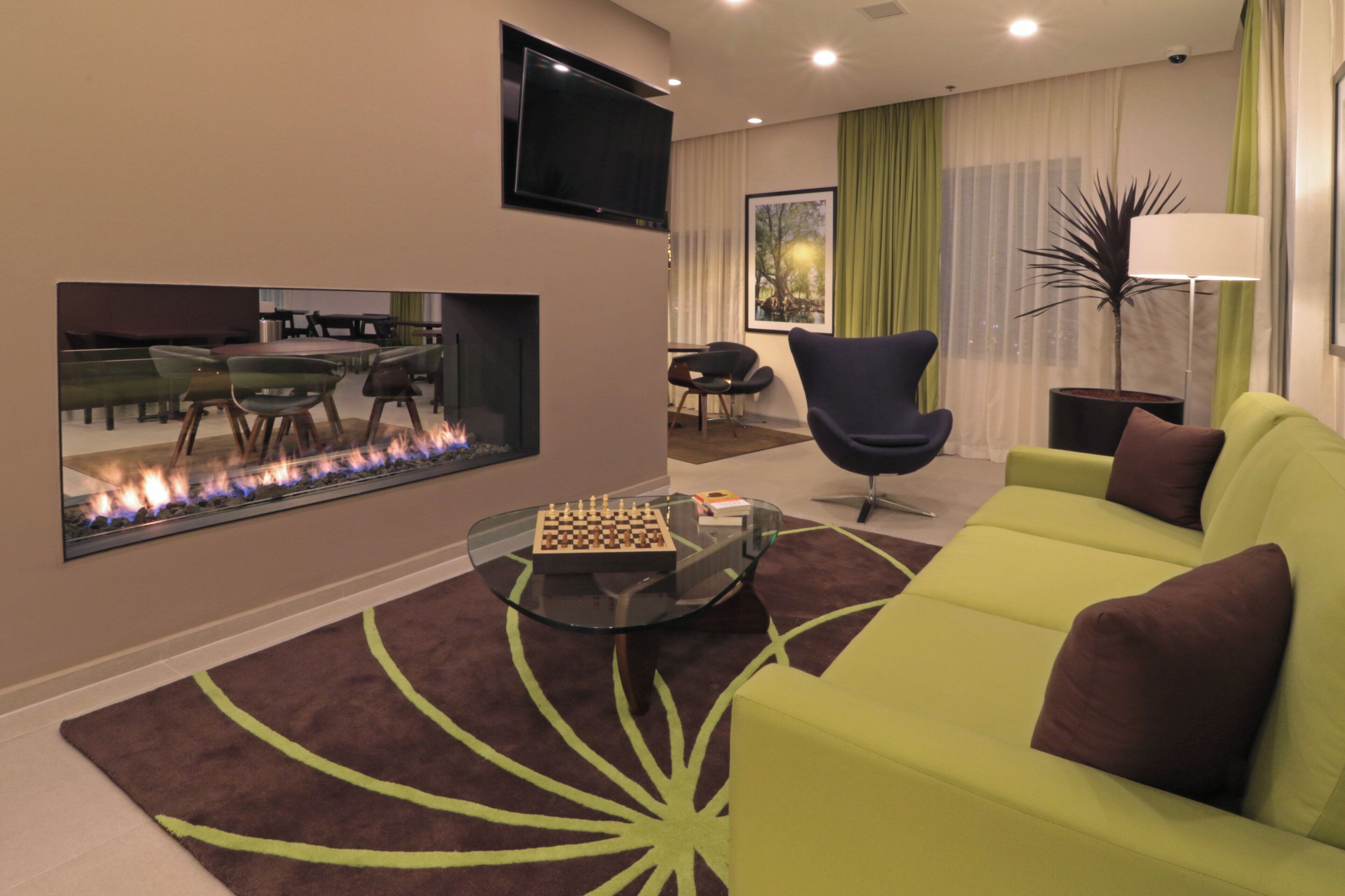 A modern living room with a fireplace, a sofa, a coffee table, and a television mounted on the wall.
