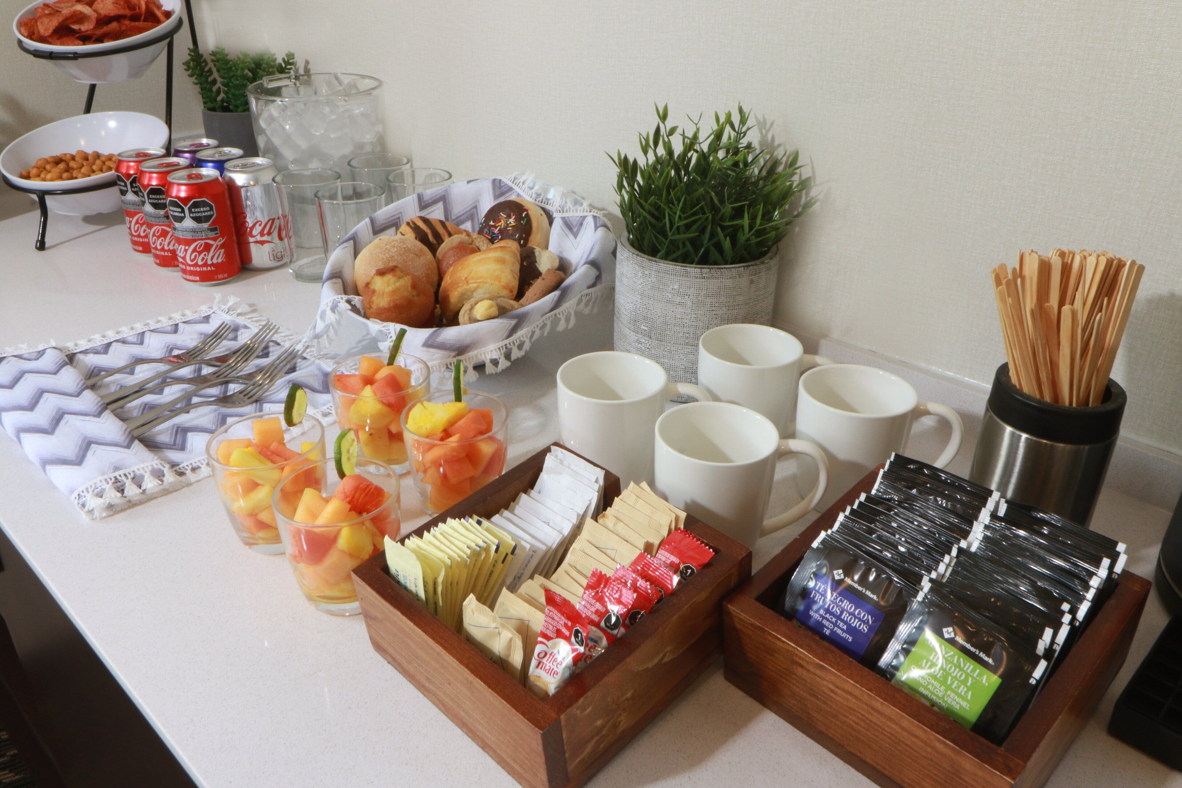 Un bufé de desayuno con diversos alimentos, bebidas y utensilios.