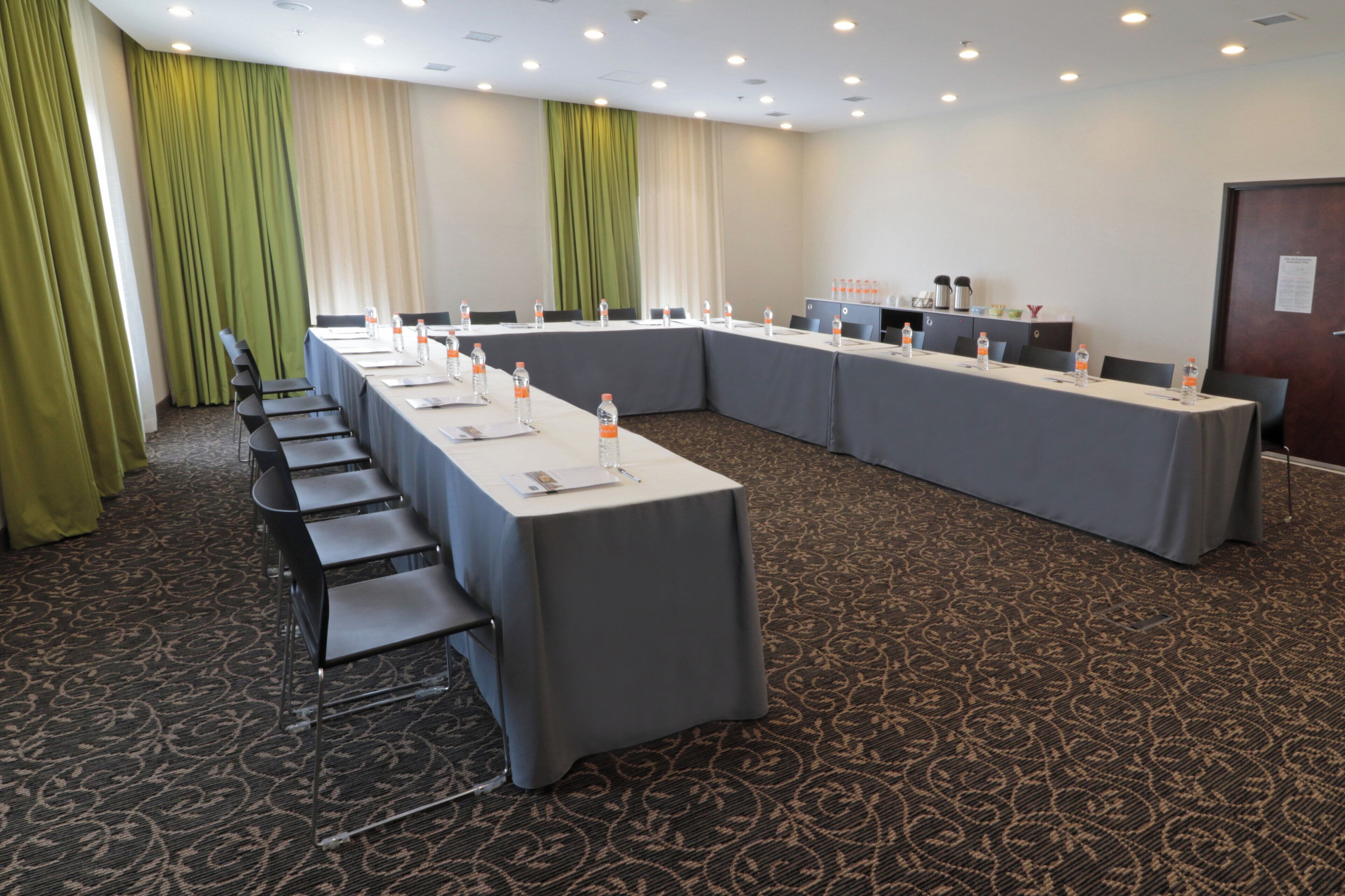 A conference room with a long table, chairs, and water bottles.