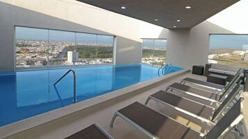A rooftop pool with clear views of a cityscape, including a prominent building and a hill.