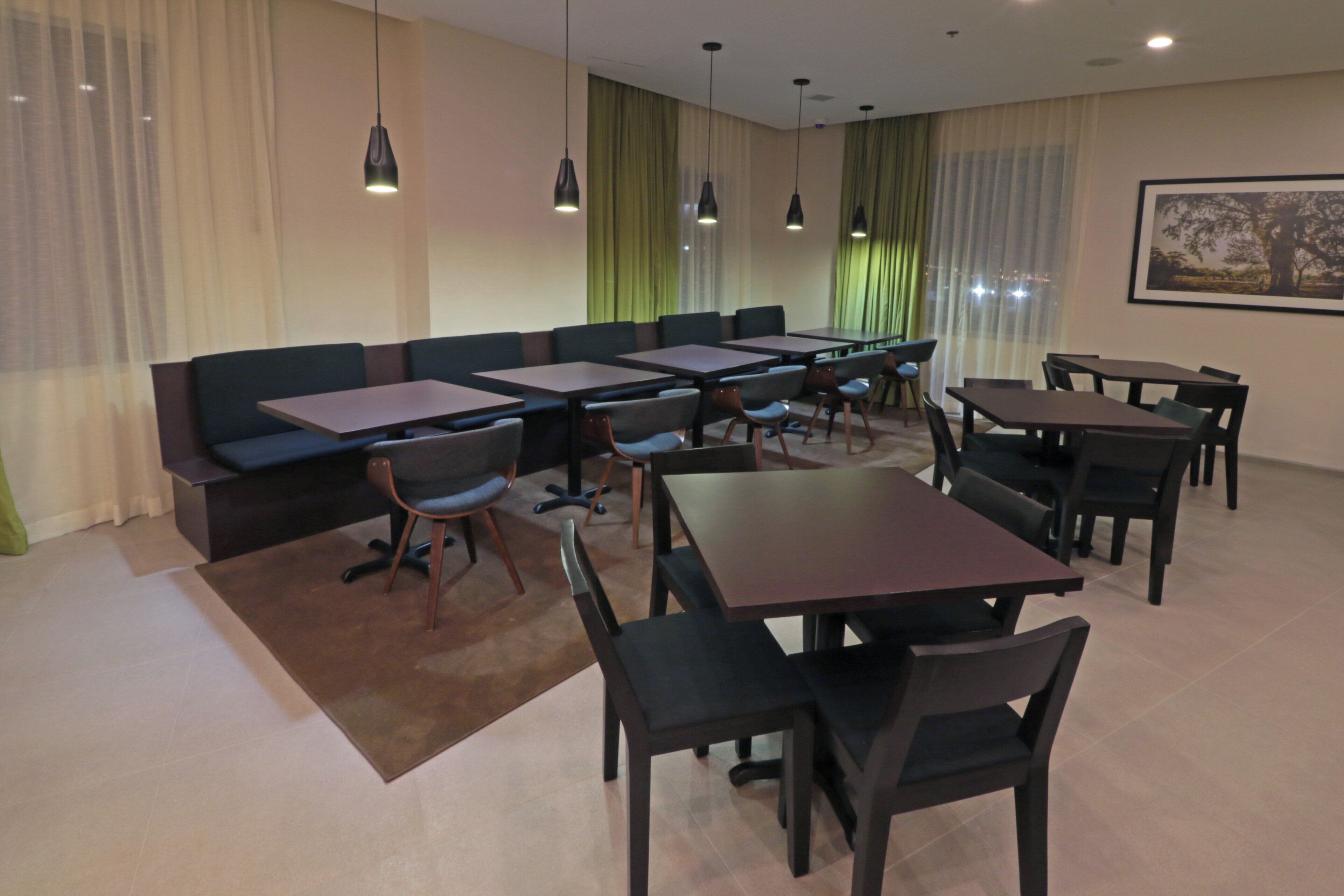 A conference room with a long table, several chairs, a sofa, and pendant lighting.
