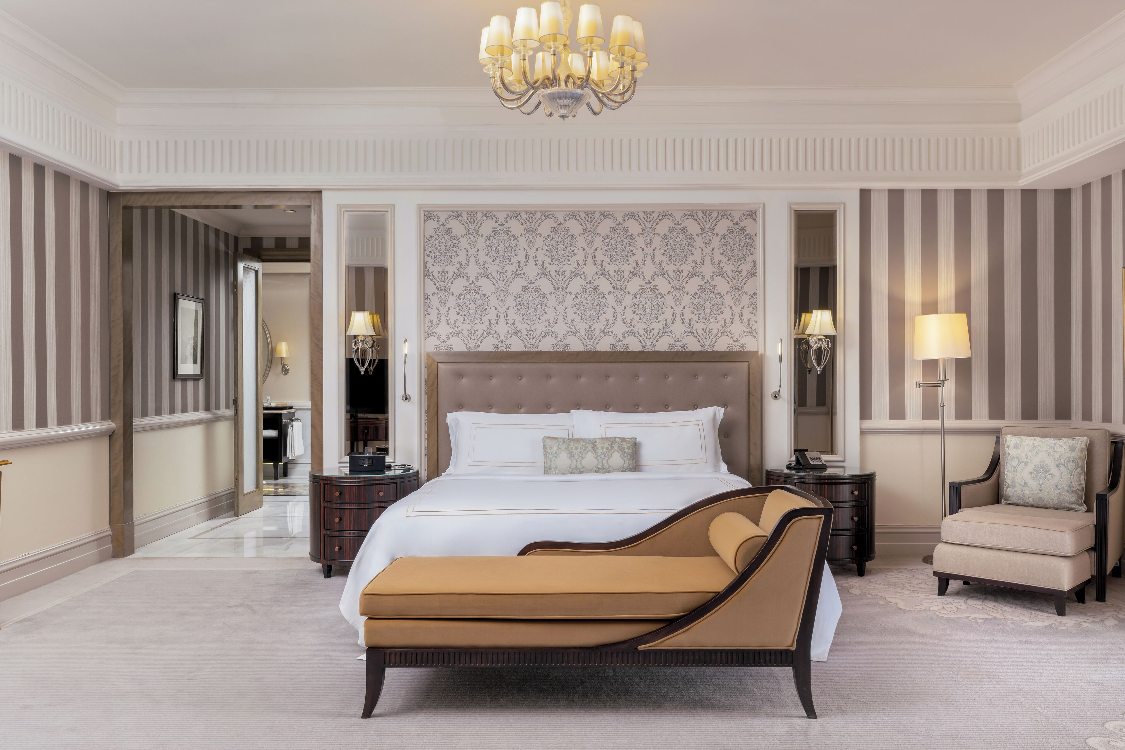Ein geräumiges Schlafzimmer mit einem großen Bett, einer Liege, einem Nachttisch und einem Sessel.