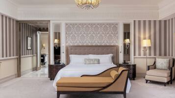 A spacious bedroom with a large bed, a chaise lounge, a nightstand, and a chair.