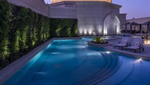 Una gran estructura abovedada iluminada, con una piscina y sillones de descanso al frente.