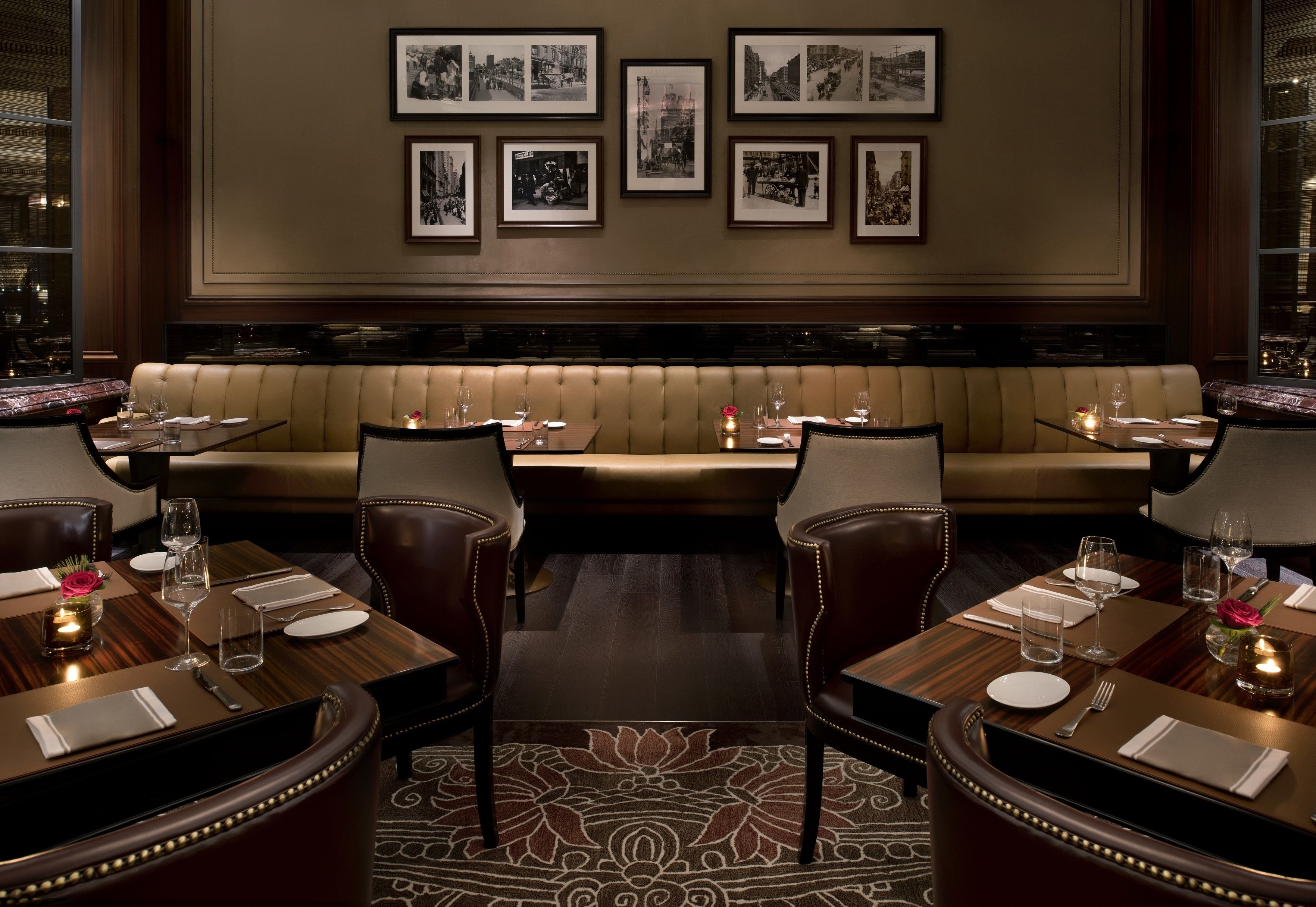 A formal dining area with leather booths, wooden tables, and framed photographs on the wall.