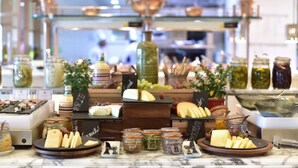 Una presentación de quesos y frutas con diferentes tipos de queso, uvas y frascos de conservas.