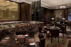 Un restaurante con mostradores de mármol, paneles de madera oscura y sillas de cuero.