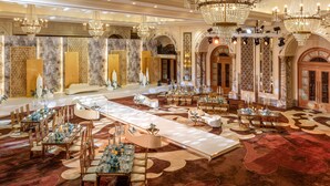 Un salón de banquetes lujoso con candelabros, decoración elaborada y una larga mesa de comedor dispuesta para un evento formal.