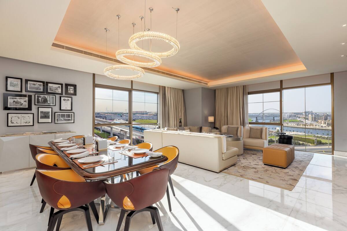 A modern living room with a dining area, large windows with a city view, and a chandelier.