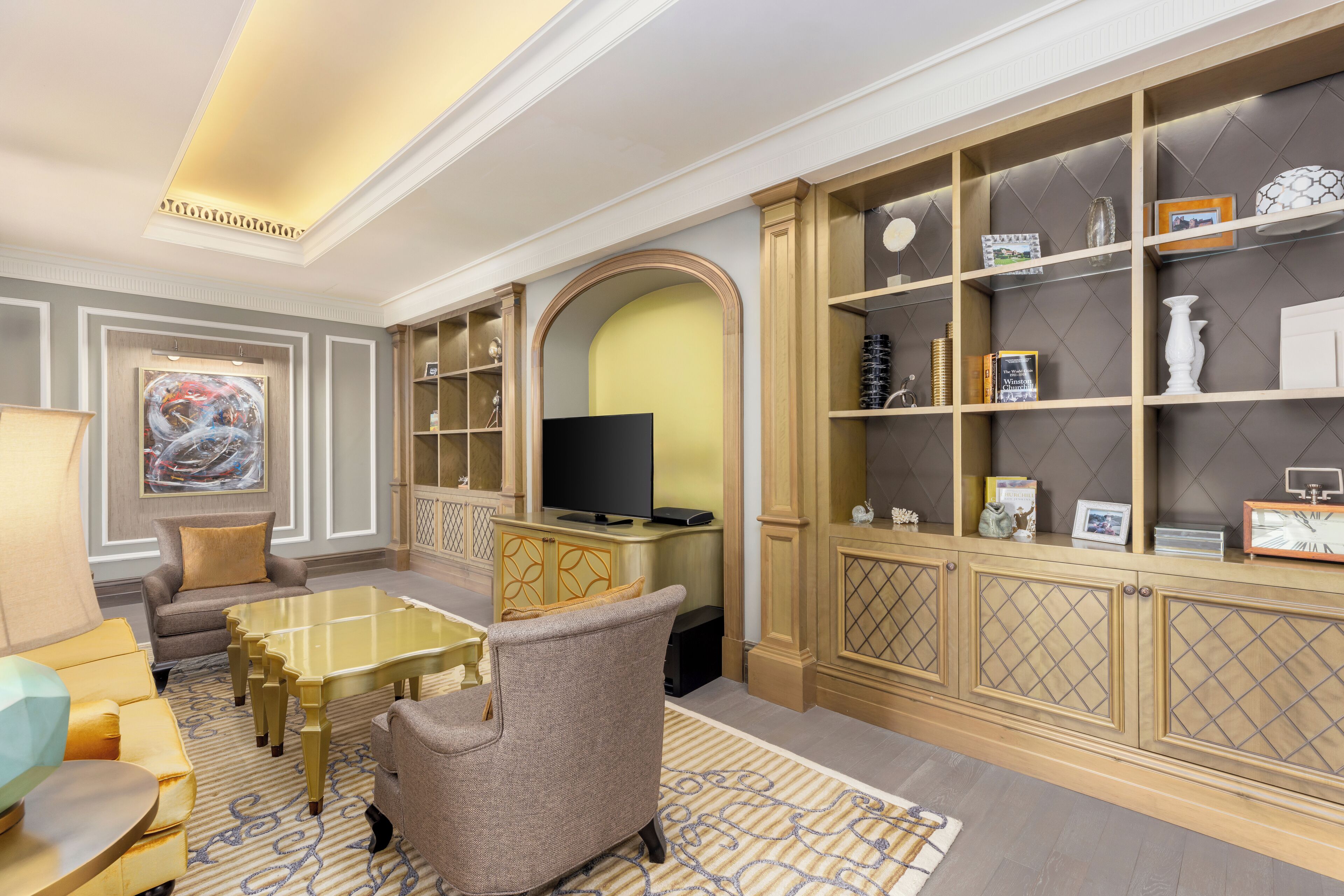 A well-appointed living room with a sofa, armchairs, a coffee table, a television, and a bookshelf.