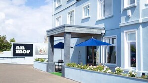 A hotel exterior with a blue facade, a covered outdoor seating area, and a sign reading "an mor". - An Mor Hotel (Bude)