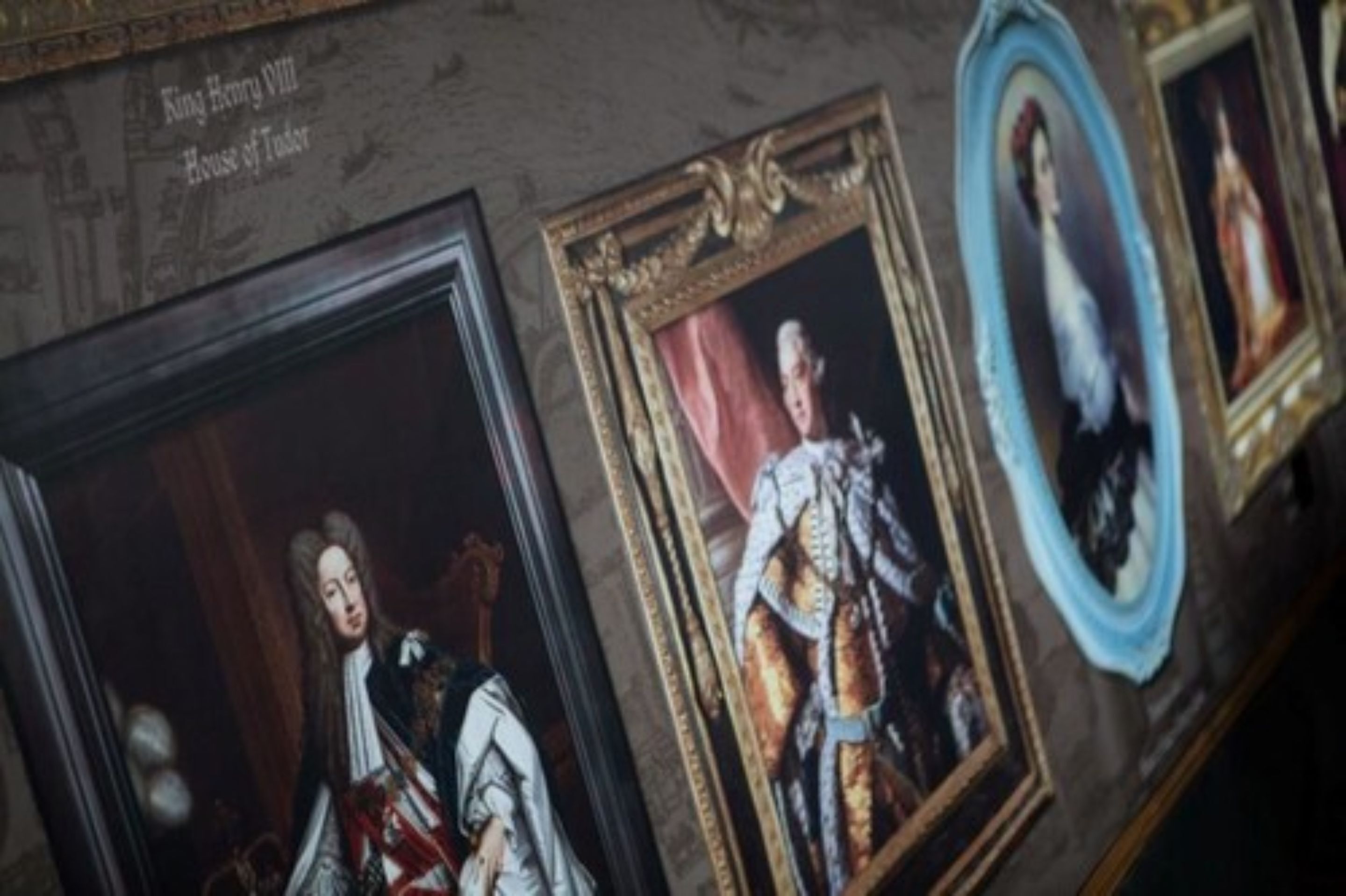 A wall with framed portraits and a plaque reading "King Henry VIII House of Tudor".