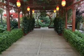 A wooden pathway leading to a covered area with lanterns and plants. - Golmud Hotel (Golmud)