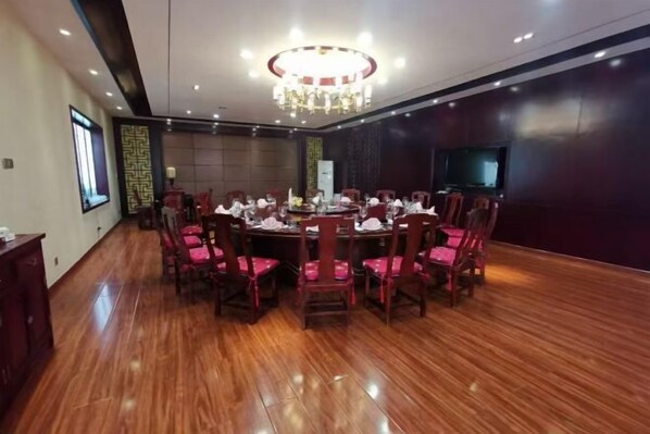 A conference room with a round table, chairs, a chandelier, a television, and a patterned wall. - Golmud Hotel (Golmud)