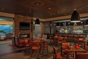 A restaurant with brick walls, a bar area, and multiple tables and chairs. - Four Points By Sheraton Midland (Midland)