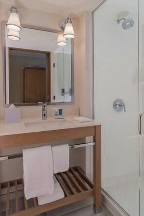 A modern bathroom with a wooden vanity, a large mirror, and a glass shower enclosure. - Four Points By Sheraton Midland (Midland)