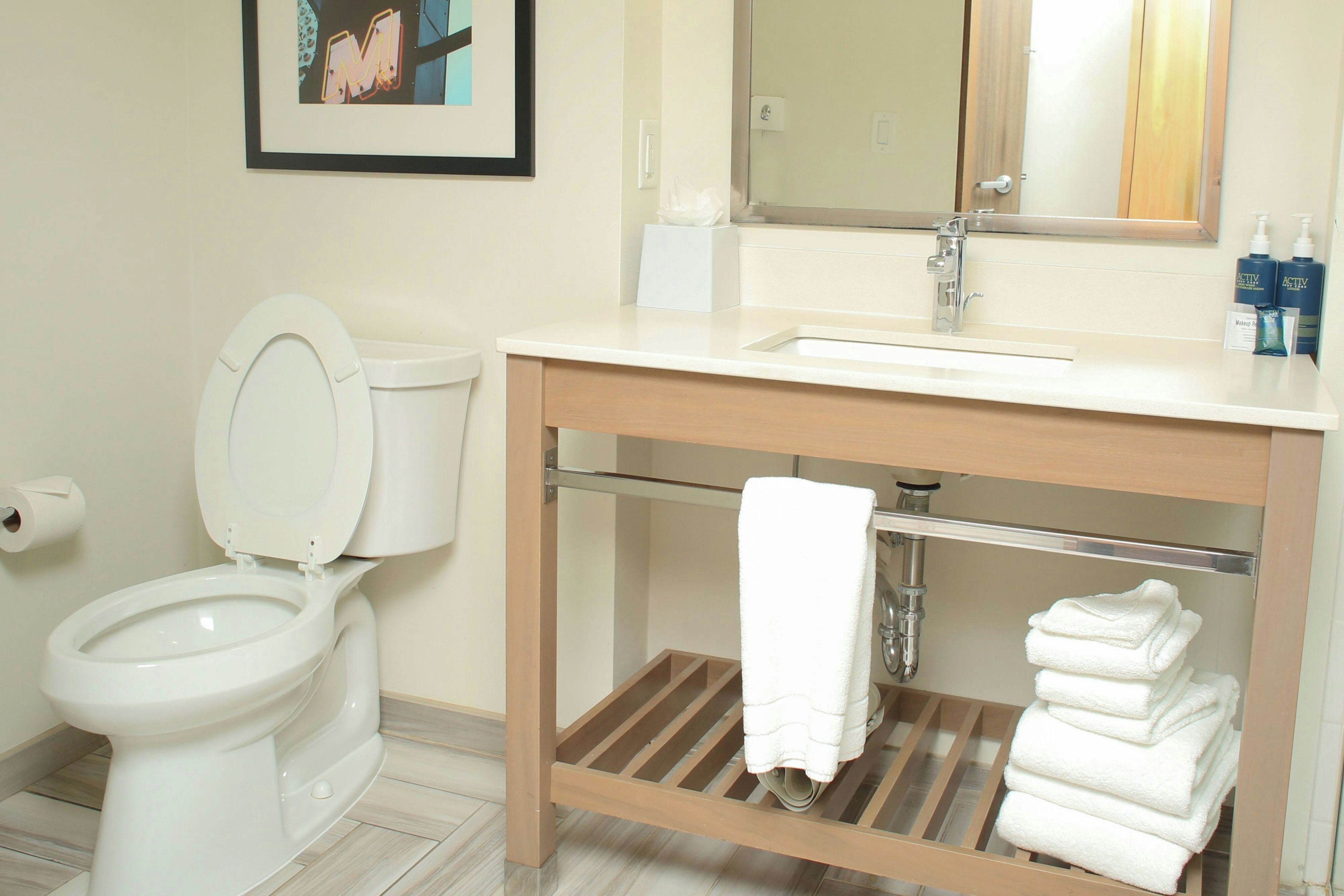 A bathroom with a toilet, sink, and a towel rack with folded towels.