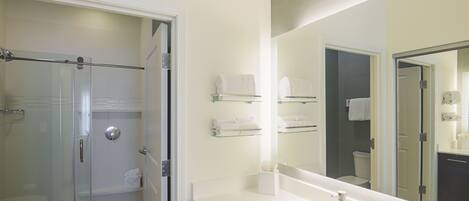 Un baño moderno con ducha de vidrio, un espejo grande y un lavabo blanco.
