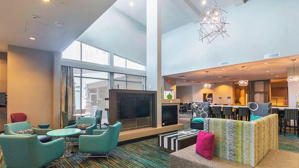 A spacious lobby with a large TV, comfortable seating, a fireplace, and a dining area.