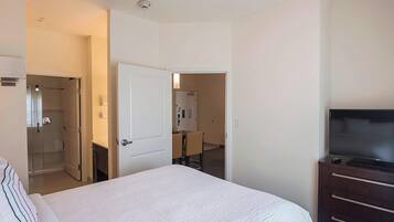Una camera d'albergo con un letto, una televisione, una scrivania e un bagno.
