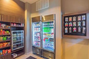 Zona de venta con opciones de bocadillos y bebidas, que incluye refrigeradores y una exhibición de agua embotellada.
