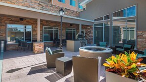 An outdoor patio area with wicker furniture, a fire pit, and a barbecue grill.