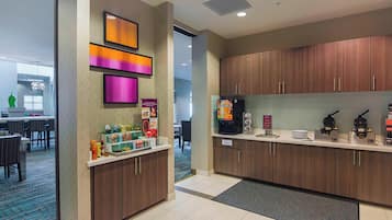 A modern kitchen with wooden cabinets, a coffee machine, and a microwave.