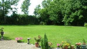 A garden with a gravel path, potted plants, and a wooden table. - Quarry Ridge B&B (Killeshin)