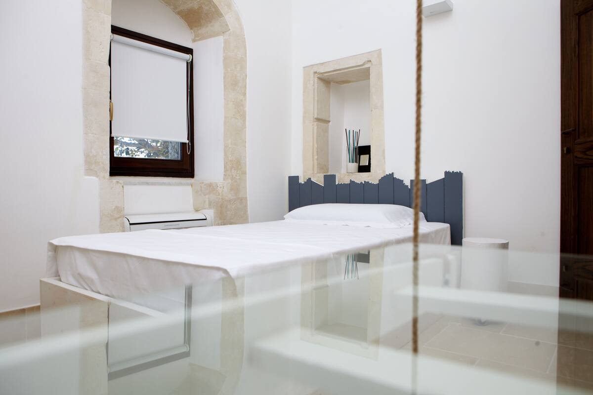 Un dormitorio minimalista con cama, ventana y espejo.