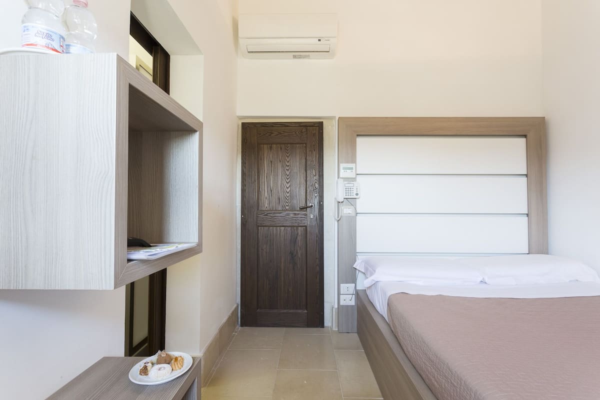 Un dormitorio pequeño y ordenado, con cama, mesita de noche, armario y puerta.
