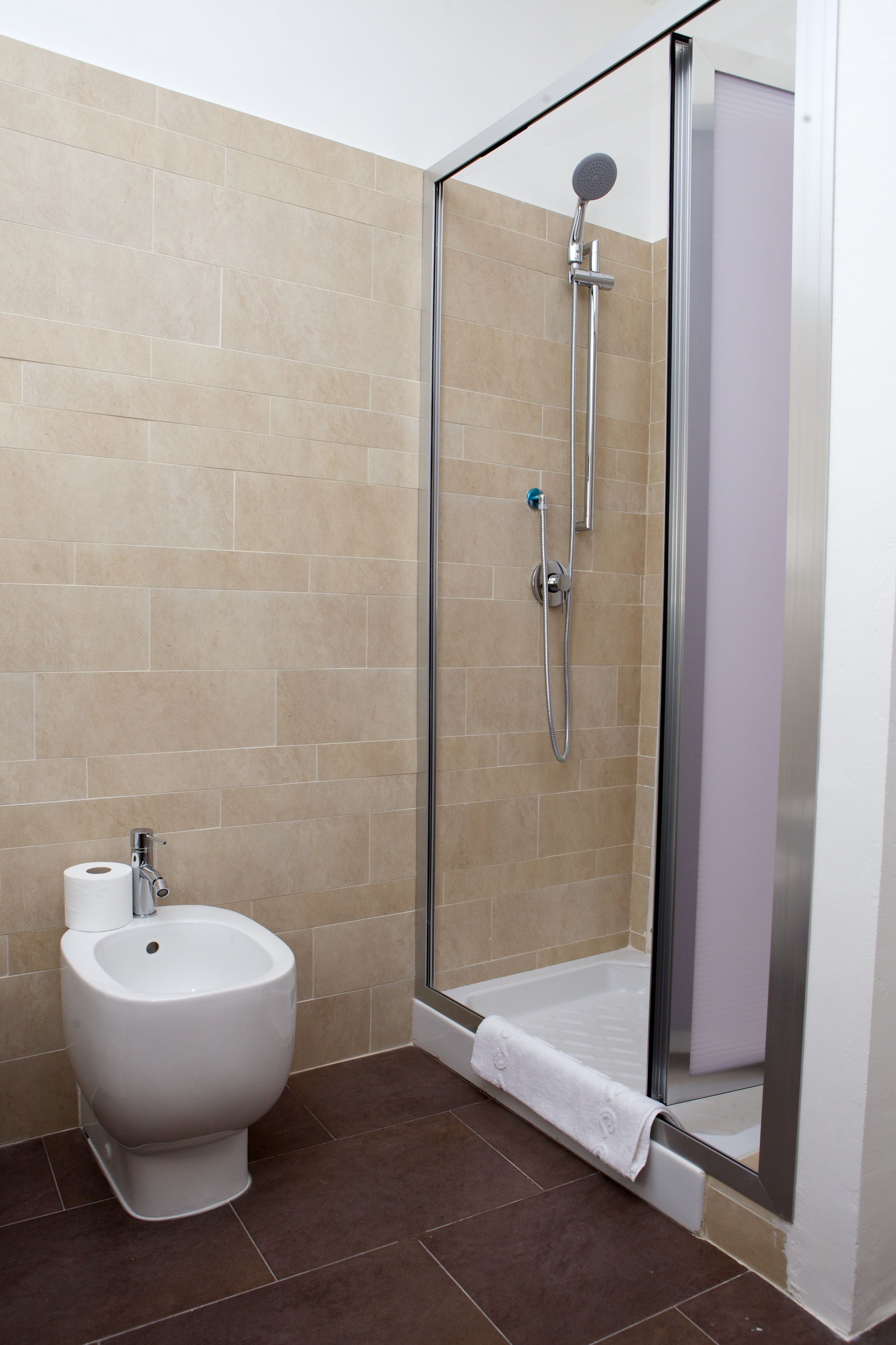 A modern bathroom with a glass-enclosed shower, a bidet, and a toilet.