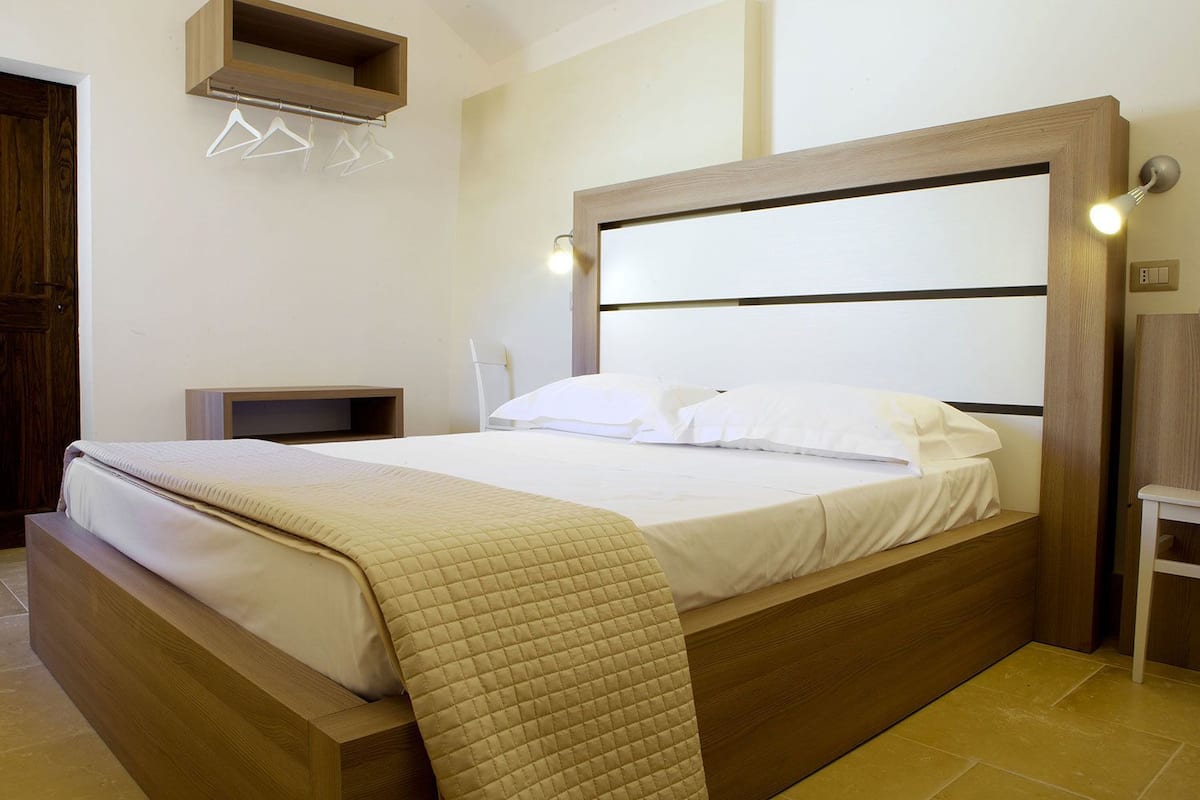 Una cama bien hecha con un edredón acolchado, un cabecero de madera y mesitas de noche.