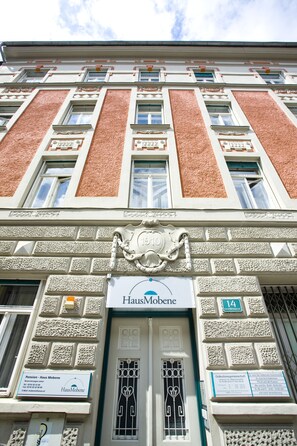 A building facade with a sign reading "Haus Mobene" and a number "14" indicating the address.
