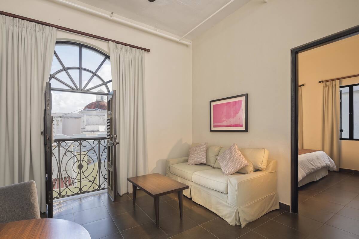 A living room with a sofa, a coffee table, and a view through a window.