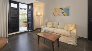 Una sala de estar con sofá, una mesa de centro, una lámpara y una puerta que da a un espacio al aire libre.