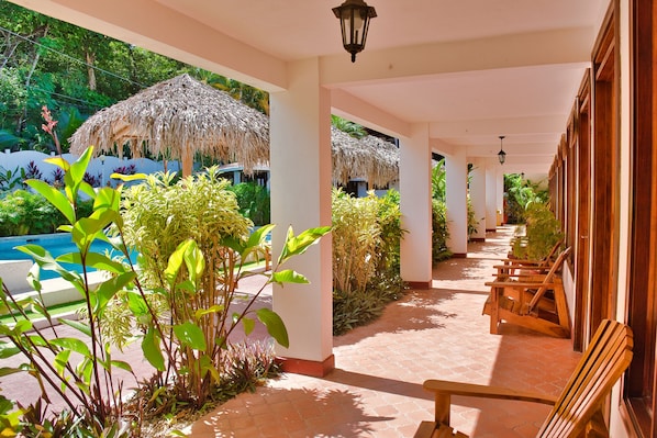 A covered outdoor area with a pool, wooden chairs, and thatched umbrellas. - Hotel Selva y Mar Sámara (Samara)