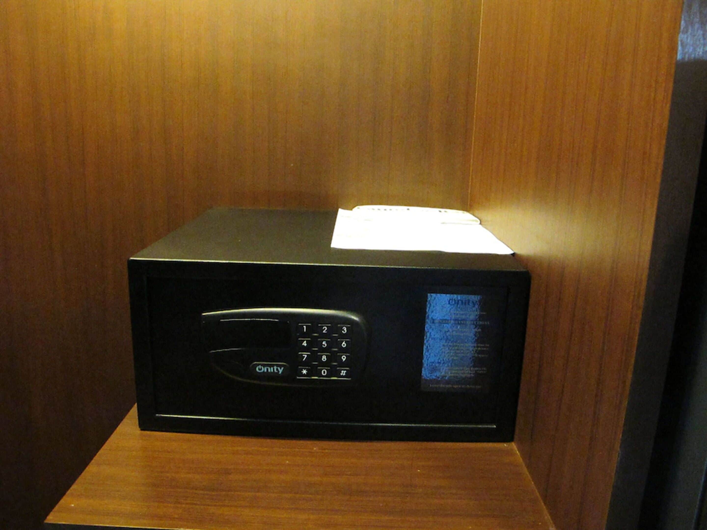 Een zwarte magnetron met een keypad en digitaal display, staand op een houten oppervlak.