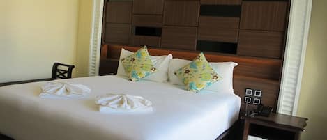 Une chambre d’hôtel avec un grand lit, une tête de lit en bois et une table de chevet avec un téléphone.