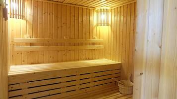 A wooden sauna with benches and a bucket.