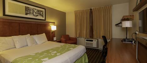 Une chambre d’hôtel avec un grand lit, un bureau avec un ordinateur, une chaise, un climatiseur et une lampe.